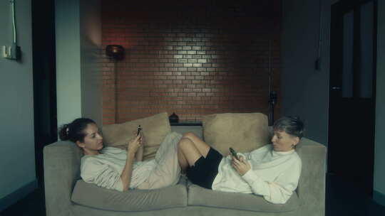 两个年轻女人拿着手机坐在家里的沙发上