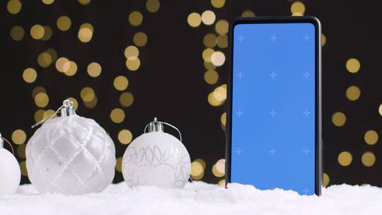圣诞装饰彩球旁的蓝屏手机