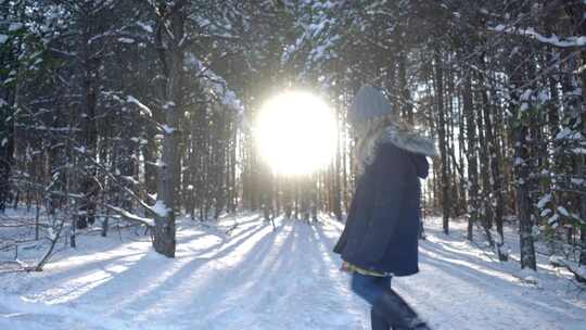 当女孩在雪地里行走时，阳光穿过松树