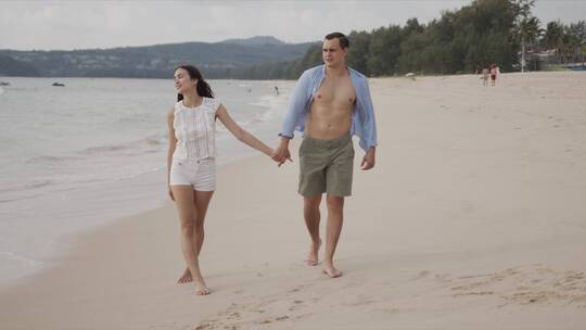 男女恋人在海边散步欣赏风景