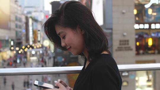 年轻美女在城市街头看手机浏览社交媒体