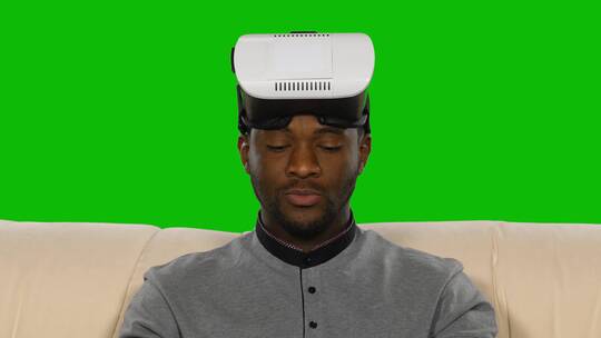 绿幕前戴着虚拟现实面目的男人