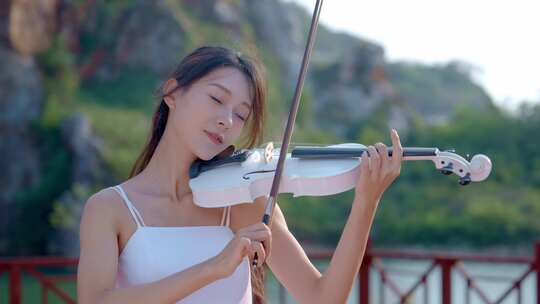 白衣女孩夕阳下河边拉小提琴歌颂美好生活