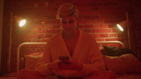 女人坐在床上看手机