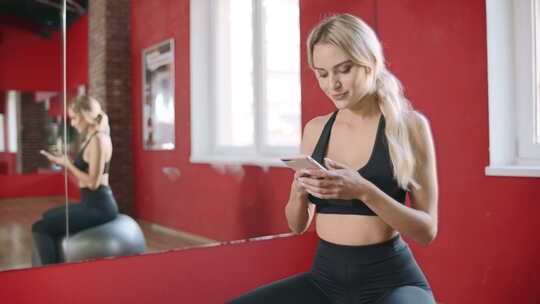 美女在健身俱乐部使用智能手机