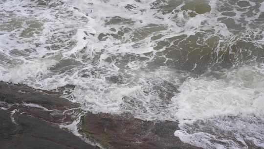 海浪拍打岩石浑浊海水冲刷礁石浪花阴天大海