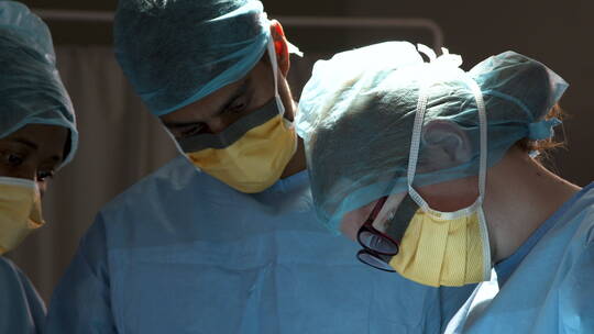 三个外科医生低头做手术视频素材模板下载