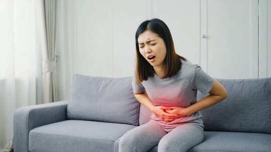 女性居家捂着肚子显痛苦
