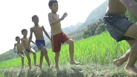 山村儿童赤脚在稻田边奔跑