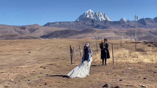 高原枯黄草原雪山情侣走向雪山拍写真婚纱
