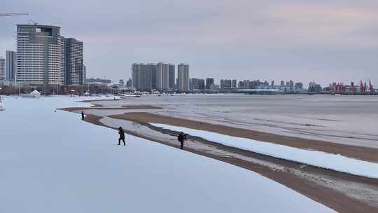 海滨城市雪后沙滩上的人们