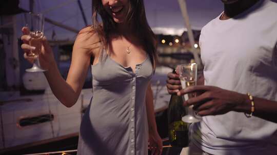 年轻的多种族夫妇手拿一杯香槟在划船派对上