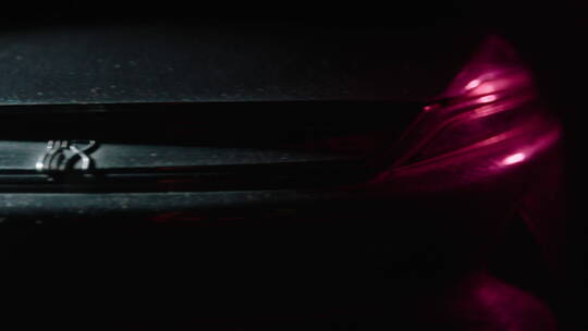 红色轿车车头特写 黑幕光线 从右到左摇拍