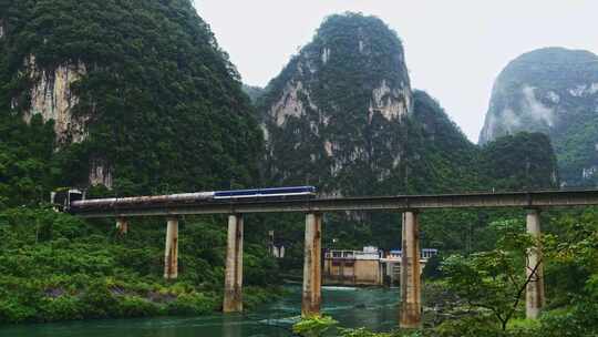 青山绿水间一列货运火车从隧道里开出