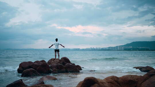 男孩在海边礁石感受海风