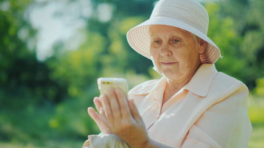 戴着帽子的老妇人在使用智能手机