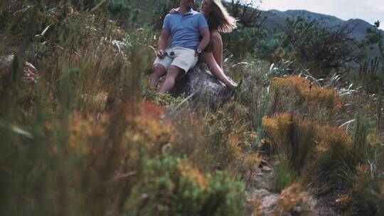 情侣坐在森林里的岩石上休息