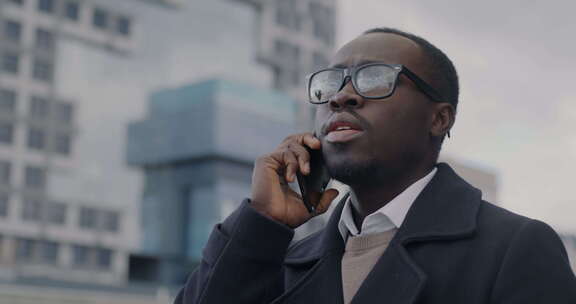 成功的非裔美国企业家在现代城市街道用手机