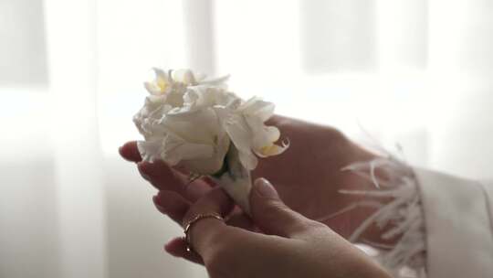59.新娘站在窗边，手里拿着婚礼胸花。准