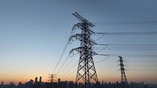 夕阳下高压电力传输线电塔剪影