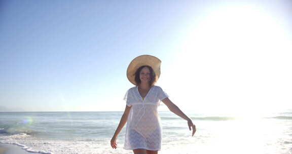 一个年轻的混血儿女人站在海滩上，戴着一顶