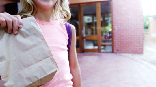 学校校园里快乐的女学生拿着纸袋的肖像