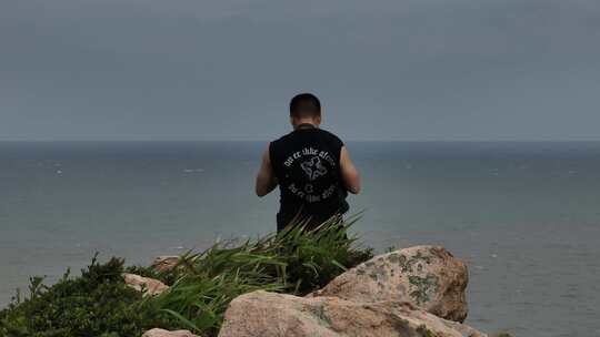 吕峡灯塔岛面向大海拍照的男子背影视频素材模板下载