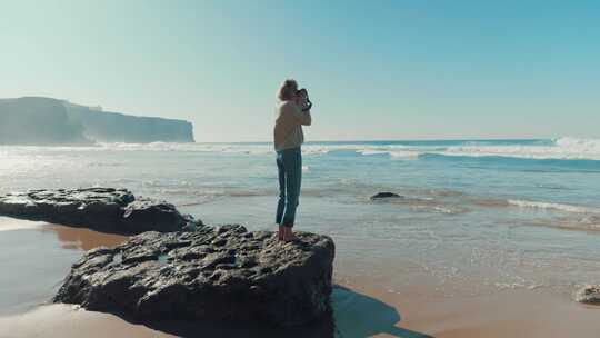 女人在海滩上散步，给海洋拍照