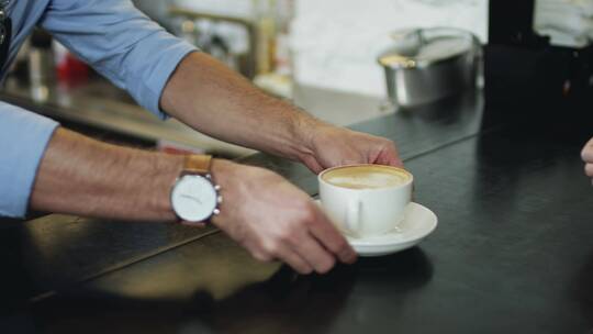 顾客从咖啡师手里接过咖啡