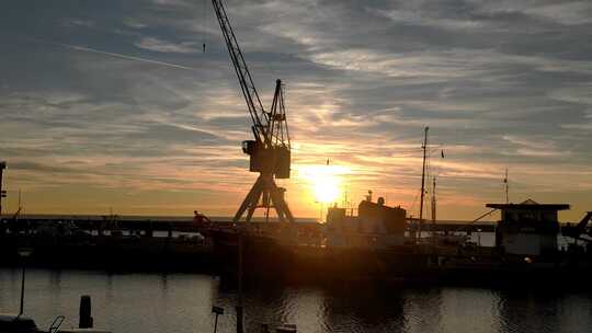 多莉拍摄了哈林根港的日落。荷兰拖船和老式起重机，背光