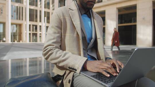 男人坐在户外使用笔记本电脑办公