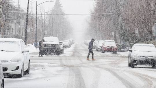 暴雪城市街道上停放的汽车 匆匆走过的行人
