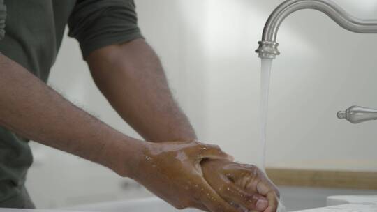 男人在水龙头下用肥皂水洗手