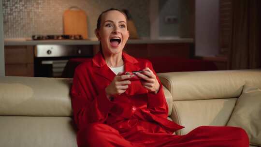 穿着红色睡衣的女人在家里的沙发上玩电子游