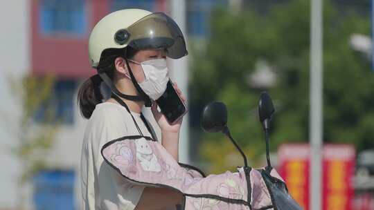 夏日道路：骑电瓶车的女孩，太阳下打电话