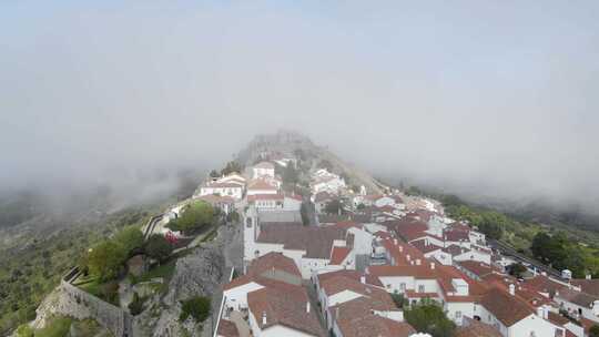 一架无人机飞过葡萄牙村庄的橙色瓦顶，进入马里奥城堡的遗迹