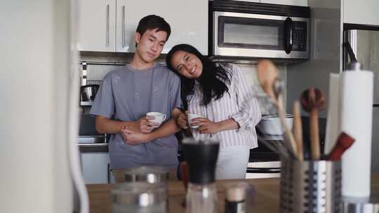 拿着咖啡杯站在厨房里的夫妇