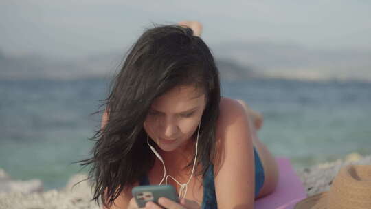 生活方式女孩躺在沙滩上用耳机听音乐
