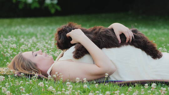 孕妇抱着狗狗躺在草坪上