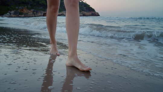 年轻女子走在海滩的水边