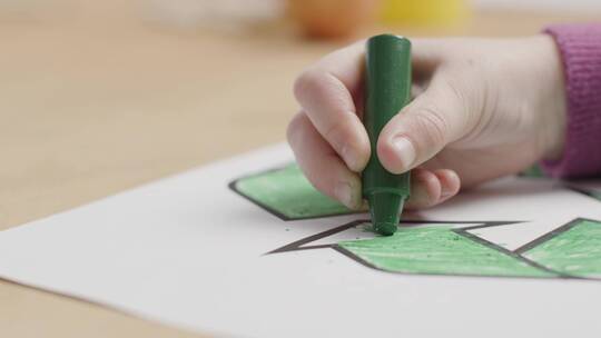 孩子使用绿色蜡笔涂色