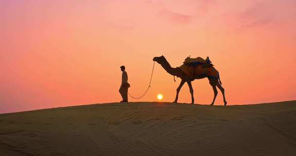 沙漠夕阳下男人牵着骆驼行走