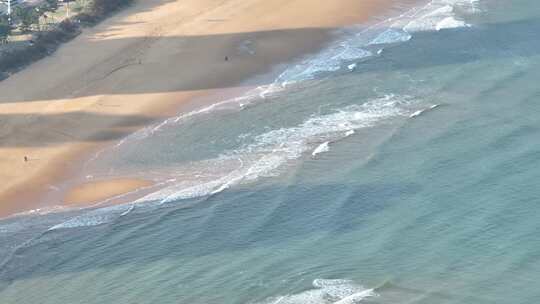 航拍俯瞰山东威海国际海水浴场沙滩上的海浪