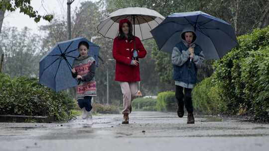 孩子们拿着雨伞在雨中蹦蹦跳跳