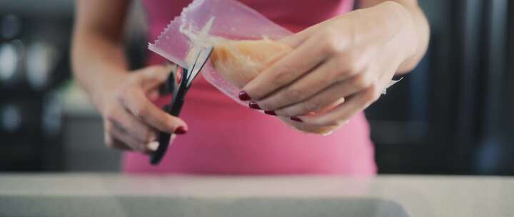 女人在厨房用生鸡肉切塑料