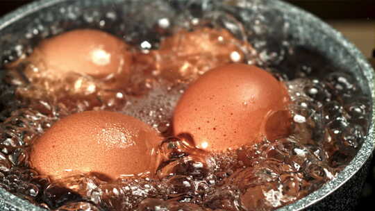 在不锈钢锅中煮沸的鸡蛋，特写镜头。沸水