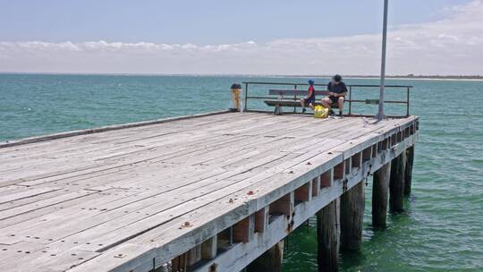 澳大利亚墨尔本海边木栈道钓鱼码头父子