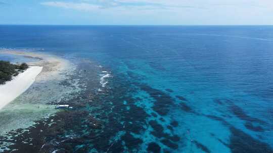 俯瞰水下珊瑚礁系统，看到一群停泊在热带蓝色岛屿上的船只