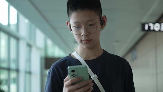 男孩子暑假出行在机场用手机