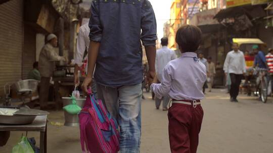 父亲和孩子牵着手走在繁忙的街道上